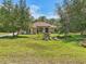 Expansive front lawn showcasing a charming one-story home, complemented by mature trees that add shade and natural beauty at 18026 Nutcracker Rd, Weeki Wachee, FL 34614