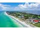 Expansive aerial view showing condos along the coastline, emphasizing beach access and tropical scenery with clear water at 2045 Gulf Of Mexico Dr # M1-207, Longboat Key, FL 34228