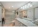 Bathroom featuring granite counters, white cabinets, decorative mirror, and glass-enclosed shower at 2045 Gulf Of Mexico Dr # M1-207, Longboat Key, FL 34228