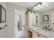 Bathroom with granite counters, white cabinets, decorative mirror, and adjacent doorway at 2045 Gulf Of Mexico Dr # M1-207, Longboat Key, FL 34228