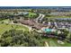 Beautiful aerial view featuring a golf course, pool area, parking area, and tropical landscaping around lush greenery at 212 River Enclave Ct, Bradenton, FL 34212