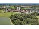 Scenic aerial view of real estate featuring a golf course, pool area, parking area, and tropical landscaping around lush greenery at 212 River Enclave Ct, Bradenton, FL 34212