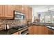 Well-equipped kitchen with granite countertop, tile backsplash, wood cabinets, and stainless steel appliances at 235 Cocoanut Ave # 108B, Sarasota, FL 34236