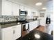 Modern kitchen with stainless steel appliances, white cabinetry, and a stylish mosaic tile backsplash at 415 Oakwood W Blvd, Sarasota, FL 34237