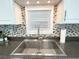 Close-up of a modern kitchen sink featuring stainless steel fixtures and a decorative mosaic backsplash at 415 Oakwood W Blvd, Sarasota, FL 34237
