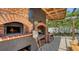Covered outdoor kitchen featuring a brick pizza oven, wood storage, and a cozy dining area at 4857 Stevens Dr, Sarasota, FL 34234