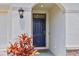 Close-up of the stylish front door with sidelight, enhanced by decorative plants and textured walls at 5121 Sultana Cv, Bradenton, FL 34211