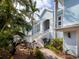 Beautiful light blue home featuring an elegant staircase, tropical landscaping and a paver walkway at 5132 Jungle Plum Rd, Sarasota, FL 34242