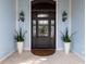 Close-up of an elegant front door with decorative glass, stylish sconces, and potted plants creating a welcoming entrance at 5132 Jungle Plum Rd, Sarasota, FL 34242