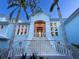 Elegant light blue home with a grand staircase, white railings, and meticulous landscaping for sophisticated curb appeal at 5132 Jungle Plum Rd, Sarasota, FL 34242