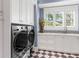 Well-lit laundry room with storage, modern washer and dryer and a patterned tile floor at 5132 Jungle Plum Rd, Sarasota, FL 34242