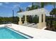 Community pool with lounge chairs beneath a pergola, framed by lush landscaping and palm trees at 5320 Tide Point Way, Bradenton, FL 34208