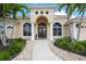 Beautiful front entrance with an arched doorway, double doors, meticulous landscaping, and white support pillars at 6143 9Th Avenue Ne Cir, Bradenton, FL 34212