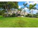Lush front lawn with mature landscaping including palms and trees leading to the beautiful tan home at 6143 9Th Avenue Ne Cir, Bradenton, FL 34212