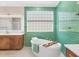 Stylish bathroom with a soaking tub, bright green tiles, and modern lighting fixtures at 7551 Calle Facil, Sarasota, FL 34238