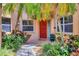 Inviting front entrance featuring a red door, tropical landscaping, and a stone pathway at 7551 Calle Facil, Sarasota, FL 34238
