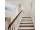 Elegant staircase with white risers, wood treads, and a wood handrail leading to a bright, open space upstairs at 7551 Calle Facil, Sarasota, FL 34238