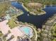 Aerial view features community pools, tennis courts, and a scenic lake with fountain at 7641 Quinto Dr, Sarasota, FL 34238