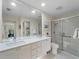 Bright bathroom featuring a double vanity with white countertops and a glass-enclosed shower at 7641 Quinto Dr, Sarasota, FL 34238