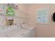Bright laundry room featuring a window with plantation shutters and white appliances at 802 Montrose Dr # 204, Venice, FL 34293