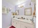 Bathroom features a double vanity, decorative mirrors, sconces, storage cabinet, and a pink rug at 9366 Westminster Ave, Englewood, FL 34224