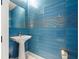Modern half bathroom with a pedestal sink and blue tiled accent wall at 111 S Pineapple Ave # 813, Sarasota, FL 34236
