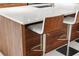Close-up of a kitchen island with a white countertop, wood paneling, and modern bar stools at 111 S Pineapple Ave # 813, Sarasota, FL 34236