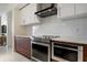 Bright kitchen with stainless steel appliances and range hood, with dark wood and white cabinets at 111 S Pineapple Ave # 813, Sarasota, FL 34236
