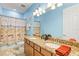 Bright bathroom features blue walls, double sinks with granite counters, large mirror, and shower with beach themed curtain at 13112 Swiftwater Way, Bradenton, FL 34211