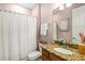 Well-lit bathroom featuring a shower with a curtain, a granite countertop, and a decorative mirror above the sink at 13112 Swiftwater Way, Bradenton, FL 34211