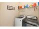 Functional laundry room equipped with a washing machine, a dryer, and shelving for storage at 13112 Swiftwater Way, Bradenton, FL 34211