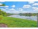 Scenic pond view reflecting blue sky and clouds, surrounded by lush green grass and neighborhood homes at 13112 Swiftwater Way, Bradenton, FL 34211