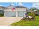 Charming home featuring a two-car garage, well-maintained lawn, and patriotic American flag at 13169 Steinhatchee Loop, Venice, FL 34293