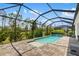 Pool with a waterfall feature and screened enclosure, with a view of the pool deck and surrounding landscape at 13169 Steinhatchee Loop, Venice, FL 34293