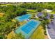 Aerial view of well-maintained tennis courts surrounded by lush greenery and a parking area at 13169 Steinhatchee Loop, Venice, FL 34293