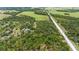 Aerial view of a wooded parcel close to a paved road and grassy, open fields at 140 Cowpen Ln, Sarasota, FL 34240