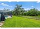 Expansive backyard with lush green grass, a screened-in pool area, and a charming wooden fence at 140 Cowpen Ln, Sarasota, FL 34240