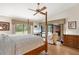 A well-lit bedroom boasts vaulted ceilings, a four-poster bed, and a view of the refreshing outdoor pool at 140 Cowpen Ln, Sarasota, FL 34240