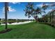 Expansive backyard with lush green grass, mature trees, and a serene waterfront view at 1542 Ormond Ter, Parrish, FL 34219