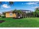 Landscaped backyard featuring a screened-in lanai, a well-manicured lawn and tropical palm trees at 1542 Ormond Ter, Parrish, FL 34219