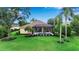 Well-manicured backyard featuring lush green grass, palm trees, and a screened-in pool enclosure at 1542 Ormond Ter, Parrish, FL 34219