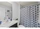 Well-lit bathroom with a stylish vanity and shower featuring a patterned curtain at 16746 Parker River St, Wimauma, FL 33598