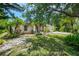 Charming home with a lush front yard featuring mature trees, landscaping, and stone accents at 1715 Fossil Dr, Englewood, FL 34223