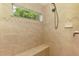 This walk-in shower features a tiled wall, a window, a showerhead, and a built-in bench at 1715 Fossil Dr, Englewood, FL 34223
