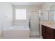 Bright bathroom featuring a garden tub, glass block window, glass-enclosed shower, and vanity sink at 20316 Natures Corner Dr, Tampa, FL 33647