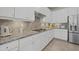 Modern kitchen with white cabinets, granite countertops, sleek cooktop, and stainless steel refrigerator at 20831 Valprato Ct, Venice, FL 34293