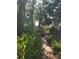 Beautiful backyard with brick pathway, mature trees, and a glimpse of the house, offering a serene outdoor retreat at 2181 Pine Gardens Trl, Sarasota, FL 34231
