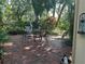 Outdoor patio with brick flooring, lush landscaping, and a dining table providing a relaxing space at 2181 Pine Gardens Trl, Sarasota, FL 34231