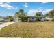 Single-story home with an attached garage and a front lawn under a bright, cloudy sky at 2606 Bismark Way, Sarasota, FL 34231