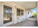Covered porch with tiled flooring, decorated with a small white table and chair set by a leaded glass front door at 2606 Bismark Way, Sarasota, FL 34231